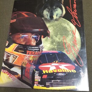 Peut inclure: Une voiture de course noire et rouge avec une grosse étoile rouge et les mots "Havoline" et "Ford" sur le côté. La voiture est conduite par Jeff Gordon, dont la signature figure en haut à droite de l'image. Une tête de loup est en arrière-plan.