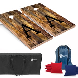 May include: A set of two wooden cornhole boards with a rustic woodgrain design and the letter "A" printed on each board. The set includes a black carrying bag, a blue drawstring bag, and eight bean bags, four red and four blue.