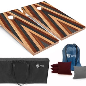 May include: A set of two wooden cornhole boards with a chevron pattern in shades of brown, black, and gray. The boards come with a carrying case, a blue drawstring bag, and eight bean bags, four red and four gray.