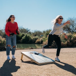 Two women playing cornhole