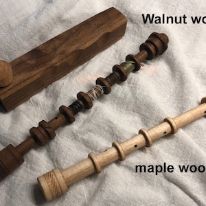 May include: A wooden box and two wooden tools are displayed on a white cloth. The box is made of walnut wood. One tool is also walnut, with spools of thread. The other tool is maple wood, with the text "maple wood".