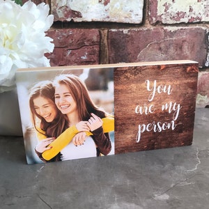 May include: A wooden block with a photo of two women smiling and hugging on one side and the text "You are my person" on the other side.