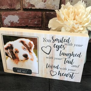 K&ouml;nnte beinhalten: Eine Holz-Gedenktafel mit einem Foto eines Hundes und dem Text "In liebevoller Erinnerung an BEAU Du hast mit deinen Augen gel&auml;chelt, mit deinem Schwanz gelacht und mit deinem Herzen geliebt".