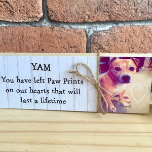 May include: A wooden memorial plaque with a photo of a dog and the text "YAM You have left Paw Prints on our hearts that will last a lifetime".