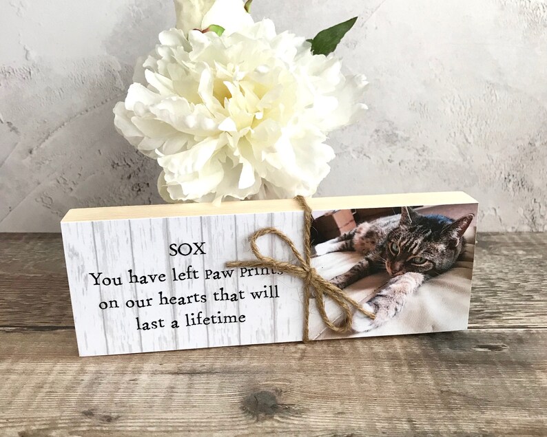 May include: A wooden block with a white background and a photo of a tabby cat. The text "SOX" is printed at the top of the block. The text "You have left paw prints on our hearts that will last a lifetime" is printed below the photo.