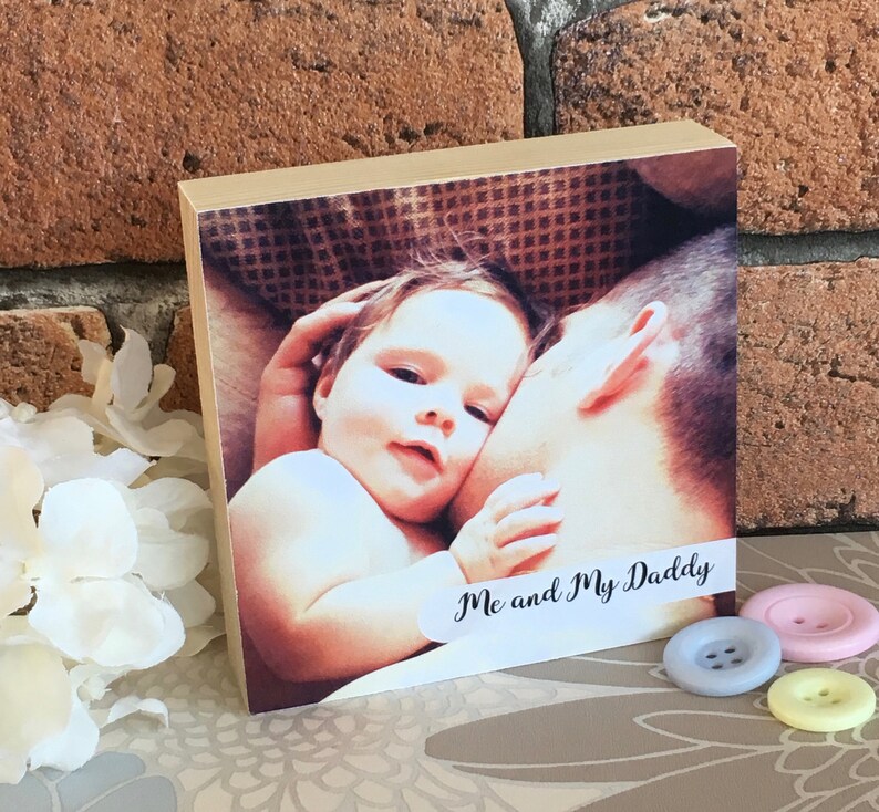 May include: A wooden photo block with a picture of a baby and a man. The baby is lying on the man's shoulder and the text "Me and My Daddy" is printed on the block.