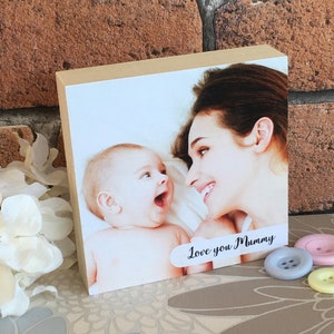 May include: A wooden photo block with a picture of a mother and child. The child is looking at the camera and smiling. The mother is looking at the child and smiling. The text "Love you Mummy" is printed on the block.