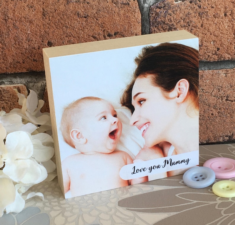 May include: A wooden photo block with a picture of a mother and child. The child is looking at the camera and smiling. The mother is looking at the child and smiling. The text "Love you Mummy" is printed on the block.