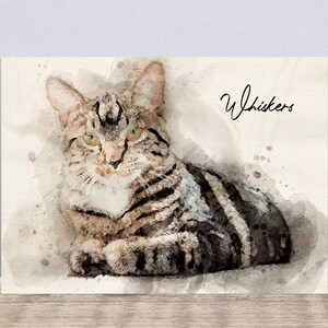 May include: Watercolor painting of a tabby cat with green eyes. The cat is lying down and looking at the viewer. The painting is titled "Whiskers".