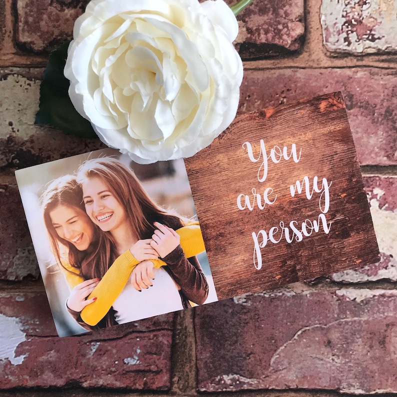 May include: A card with a woodgrain background and the text "You are my person" in white script. The card is next to a photo of two women smiling and hugging.