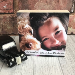 May include: A wooden photo block with a picture of a young girl and a dog. The text "To Grandad, Lots of Love Phoebe xxx" is printed on the block.