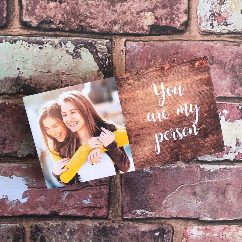 May include: A wooden sign with the text "You are my person" in white script. A photo of two women hugging is attached to the sign.