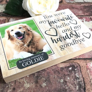 Puede incluir: Una placa de madera conmemorativa con una foto de un perro golden retriever. La placa tiene el texto "You were my favourite hello and my hardest goodbye" con corazones alrededor del texto. La placa tambi&eacute;n tiene una peque&ntilde;a etiqueta negra con el texto "In loving memory of GOLDIE".