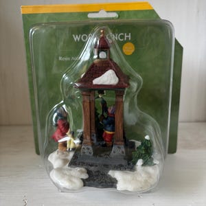 May include: A resin accessory in a clear plastic package. The accessory is a miniature winter scene with a gazebo, figures, and snow. The gazebo has a brown roof and pillars. The figures are wearing winter clothing.