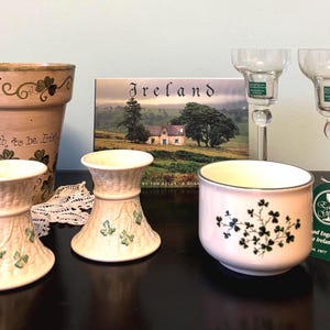 May include: A collection of Irish-themed home decor items. Includes a large terracotta pot with the text "enough to be Irish", two glass candle holders, two small decorative vases, a small bowl, and a book titled "Ireland".