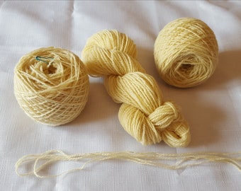 May include: Three balls of pale yellow yarn, one is wound into a ball, one is loose and one is in a skein.