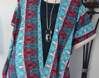 May include: A red, turquoise, and white patterned kimono-style cardigan with a silver chain necklace. The cardigan has a V-neck and short sleeves.