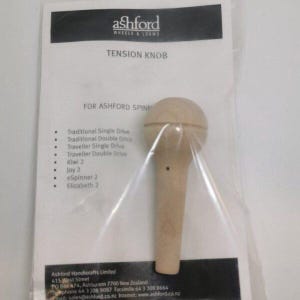 Può includere: Un pomello di tensione in legno per filatoi Ashford, confezionato in plastica trasparente. La confezione include il testo "TENSION KNOB" e un elenco di modelli compatibili. Il pomello ha una parte superiore arrotondata e un'impugnatura cilindrica.