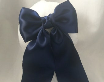 May include: A large navy blue satin bow with long tails. The bow is tied in a knot and the tails are hanging down.