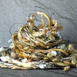 May include: A pile of yarn in shades of brown, white, and black. The yarn is arranged in a loose, tangled heap, creating a textured and organic look.