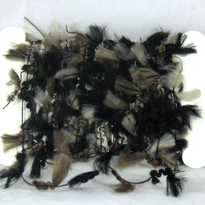 May include: A spool of black and brown fuzzy trim with long strands of fringe. The trim is wrapped around two white cardboard spools.