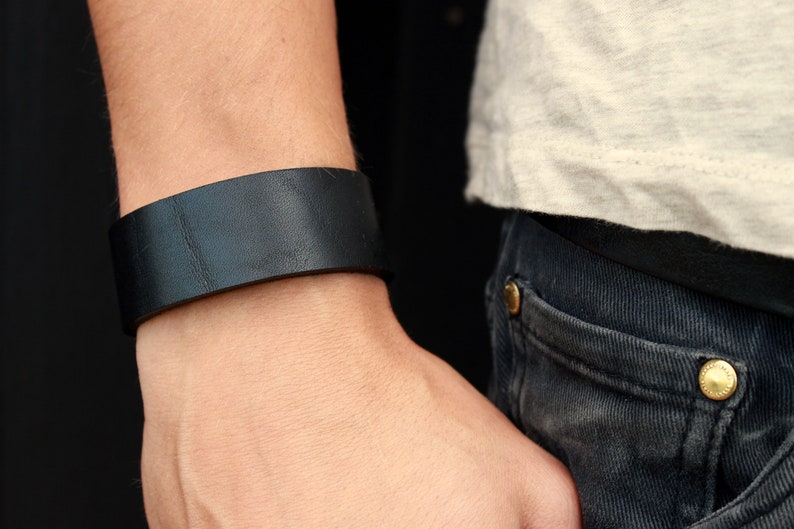May include: A black leather bracelet on a person's wrist.