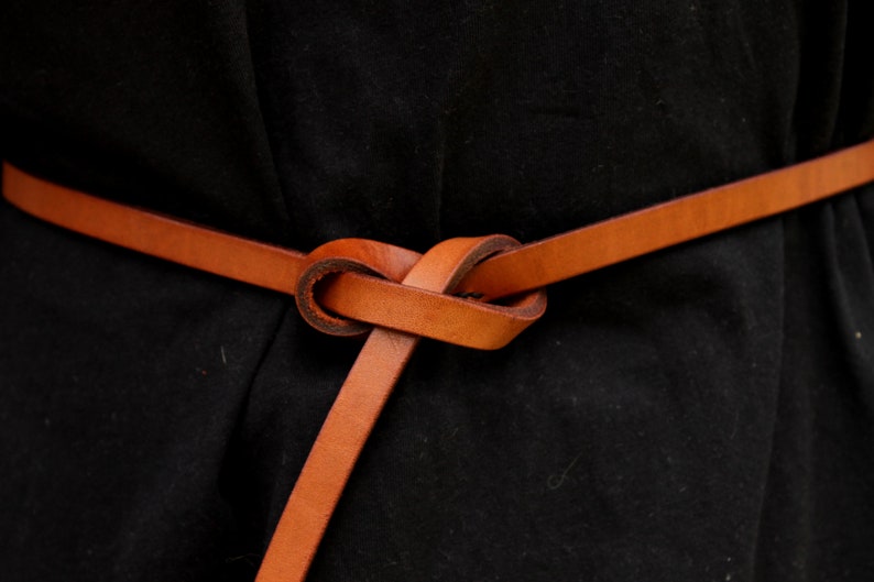 May include: A brown leather belt tied in a knot around a black garment.