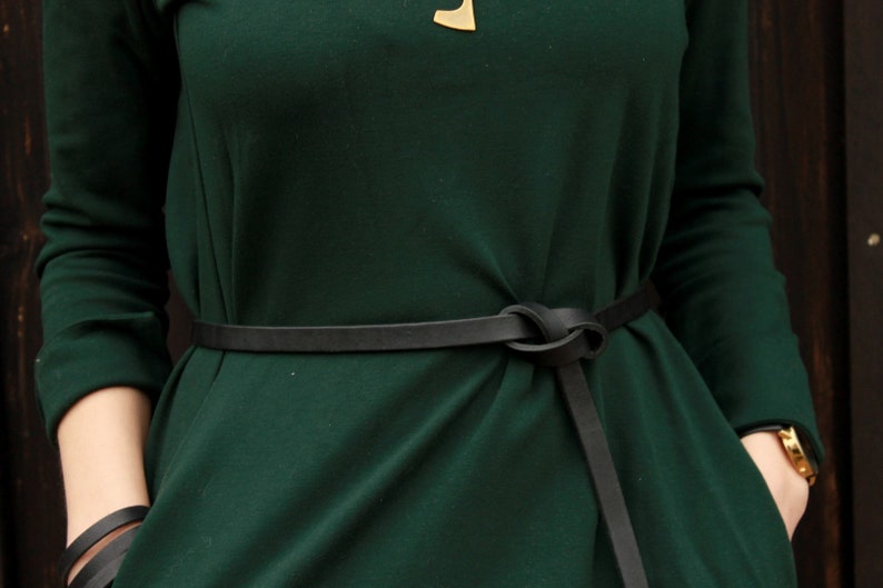 May include: A dark green dress with a black leather belt tied in a knot at the front.