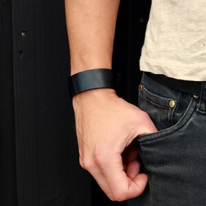 May include: A black leather bracelet on a person's wrist.