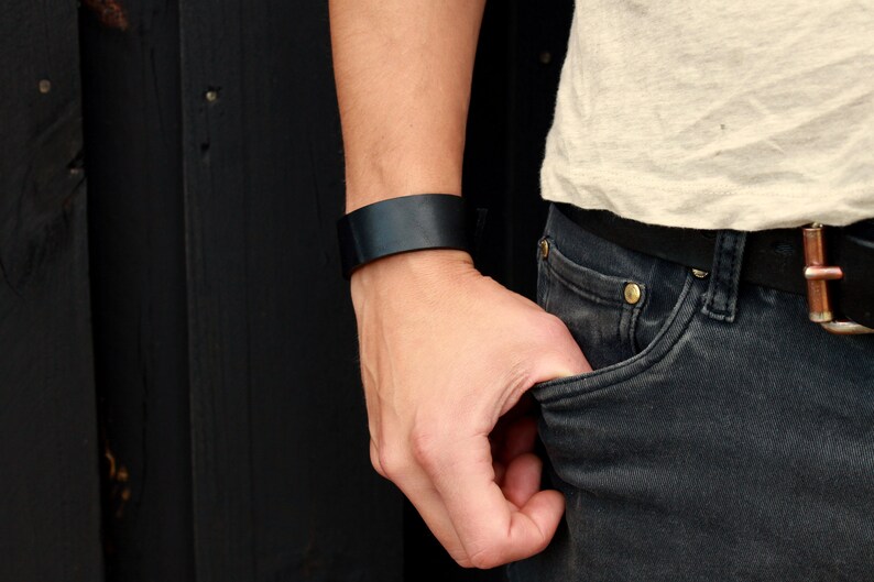 May include: A black leather bracelet on a person's wrist.