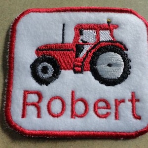 May include: Red embroidered tractor with a white background and the name Robert in red embroidery.