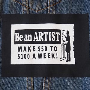 Op de afbeelding: Detail van een spijkerjasje met een zwart rechthoekig embleem. Het embleem toont witte tekst: "Be an ARTIST MAKE $50 TO $100 A WEEK!". Een silhouet van een kunstenaar is ook zichtbaar.