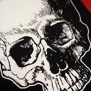 May include: A black and white illustration of a human skull. The skull is drawn in a detailed, realistic style, with visible teeth and eye sockets.