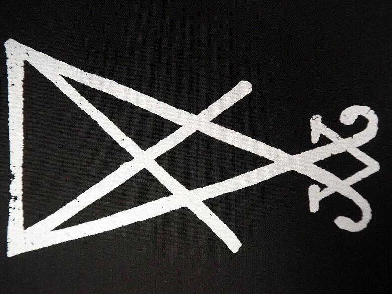 K&ouml;nnte beinhalten: Wei&szlig;es, stilisiertes Sigill auf schwarzem Hintergrund. Das Design zeigt ein Dreieck, ein Kreuz und eine Reihe geschwungener Linien. Das Bild hat ein strukturiertes Aussehen, das auf einen Druck oder eine bemalte Oberfl&auml;che hindeutet. Die Gesamt&auml;sthetik ist minimalistisch und symbolisch.