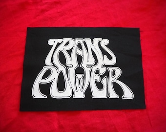 May include: Black patch with white lettering that reads "TRANS POWER" in a stylized font.
