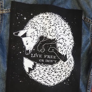 Könnte beinhalten: Schwarzer Patch mit einer weißen stilisierten Illustration eines Fuchses, der sich mit seinem Schwanz um seinen Körper zusammengerollt hat. Der Fuchs ist von weißen Sternen umgeben. Der Text "LIVE FREE OR DON'T" ist unter dem Fuchs gedruckt.