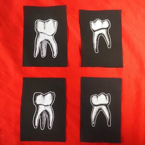 Pu&ograve; includere: Quattro toppe di tessuto nero con contorni bianchi di un dente. Ogni toppa presenta un angolo diverso del dente.