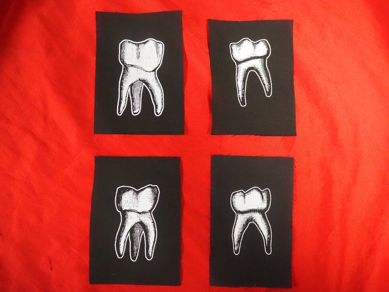 Pu&ograve; includere: Quattro toppe di tessuto nero con contorni bianchi di un dente. Ogni toppa presenta un angolo diverso del dente.