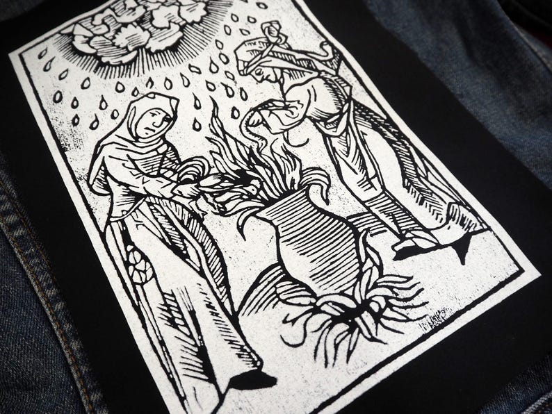 May include: Black and white patch featuring a woodcut-style illustration of two figures tending a vase with flames. Rain falls from a stylized sun above. The patch is rectangular and set against a denim jacket.