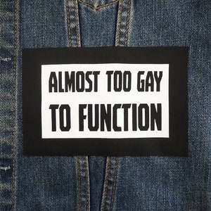 May include: A black and white patch with the text "Almost Too Gay To Function" on a denim jacket.
