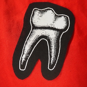 Pu&ograve; includere: Un'illustrazione in bianco e nero di un dente su uno sfondo di tessuto rosso.