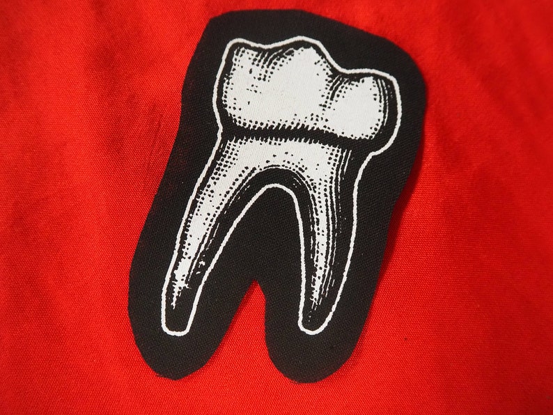 Pu&ograve; includere: Un'illustrazione in bianco e nero di un dente su uno sfondo di tessuto rosso.