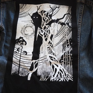 Könnte beinhalten: Schwarz-weißes Grafikdesign-Patch mit einem Baum mit Gesicht und Wurzeln. Das Patch ist auf eine Jeansjacke genäht.