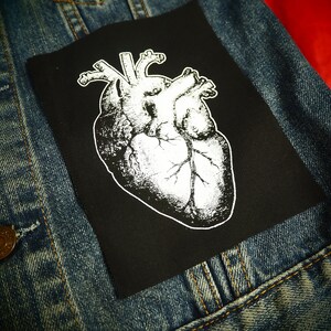 May include: A black iron-on patch with a white anatomical heart illustration.