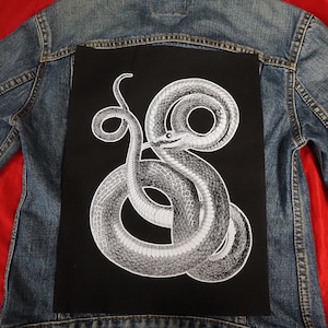 Peut inclure: Un patch noir avec une image détaillée en blanc d'un serpent enroulé sur lui-même.