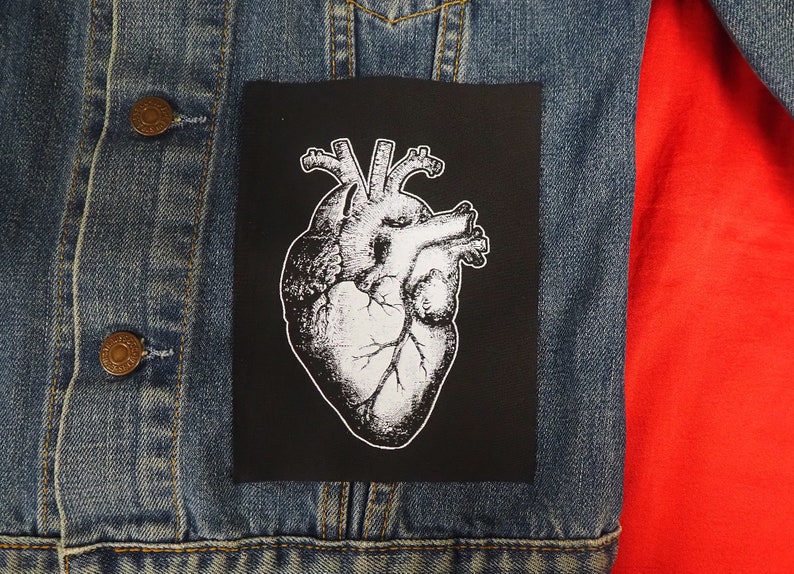 May include: A black and white anatomical heart illustration patch on a denim jacket. The patch is sewn onto the jacket.