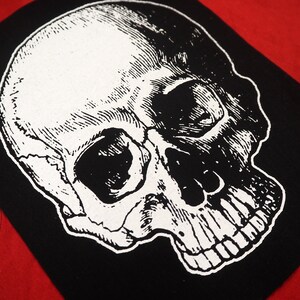 May include: Black and white iron-on patch featuring a detailed anatomical skull illustration.