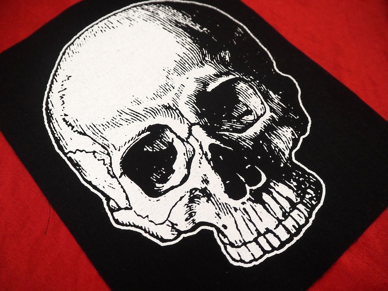 May include: Black and white iron-on patch featuring a detailed anatomical skull illustration.