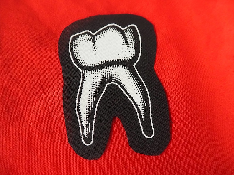 Pu&ograve; includere: Una toppa termoadesiva in bianco e nero di un dente con un design dettagliato.