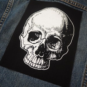 May include: A black and white skull patch with a detailed illustration of a human skull. The skull is facing to the right and has a white outline.